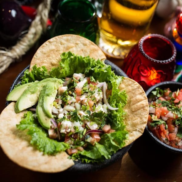 Fresh ceviche served on tostadas with avocado, lettuce, and a side of pico de gallo.