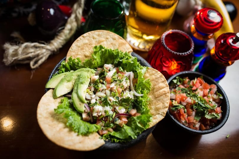Fresh ceviche served on tostadas with avocado, lettuce, and a side of pico de gallo.