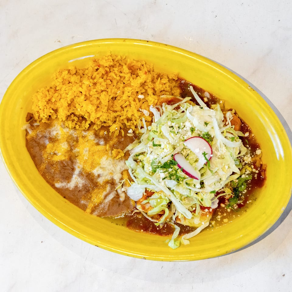 Mexican combo plate with yellow rice, refried beans, and enchiladas topped with lettuce, cheese, and radish.