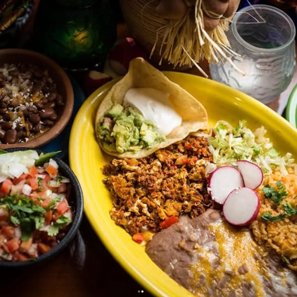 A vibrant Mexican platter with chorizo and eggs, rice, beans, pico de gallo, and a taco.